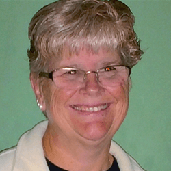 Karen, an older white woman with glasses, smiles at the camera